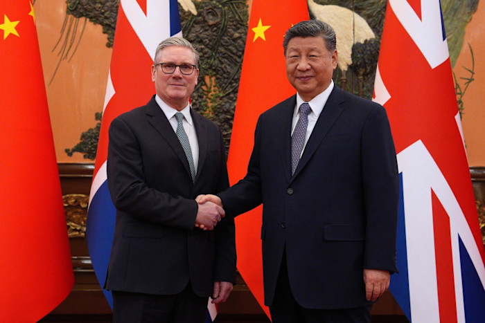 Keir Starmer shakes hands with Xi Jinping in front of British and Chinese flags before a meeting in Beijing.