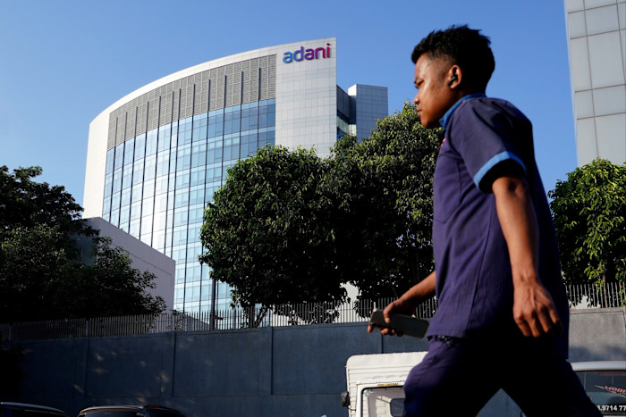 A man walks past the glass-fronted Adani Group headquarters building.