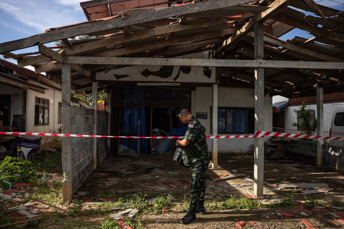 A Thai soldier stands in front of destroyed homes in Sisaket province near the border iwth Cambodia, in August