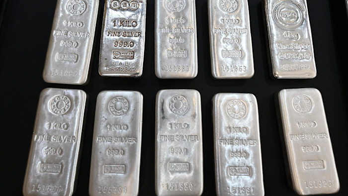 Several 1kg silver bars stamped with purity and assay marks are arranged in rows on a dark surface.