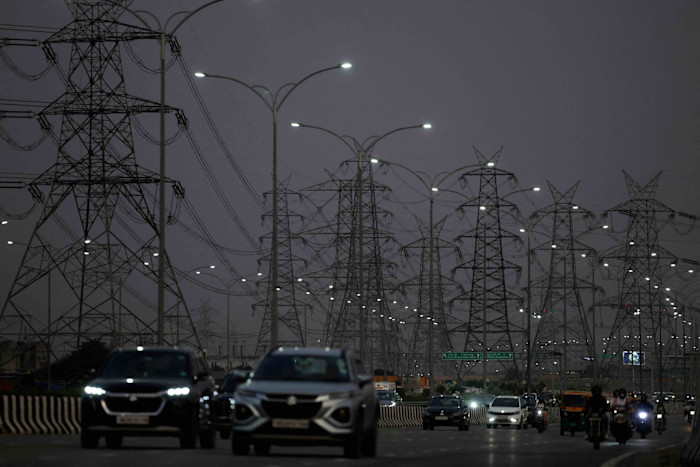 Vehicles move past electricity pylons in Gurugram, India