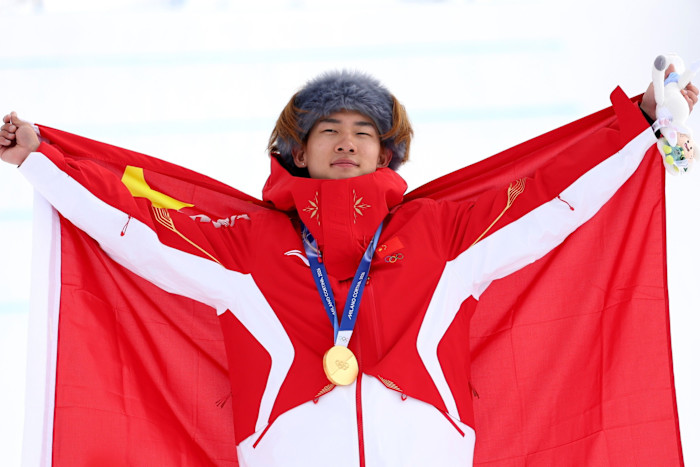 Yiming Su holds the Chinese flag and wears his gold medal during the Men’s Snowboard Slopestyle medal ceremony at the 2026 Winter Olympics.