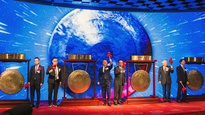James Peng, center left, and Tony Han, right, stand with others holding mallets in front of gongs at the Hong Kong Stock Exchange listing ceremony.