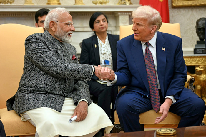Trump and Modi shake hands and smile while seated together in the Oval Office in February 2025.