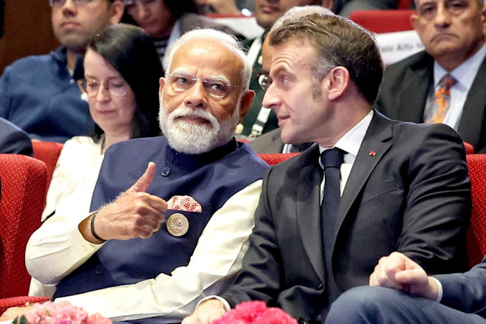Narendra Modi gives a thumbs up while seated next to another global leader at the India AI Impact Summit opening ceremony.