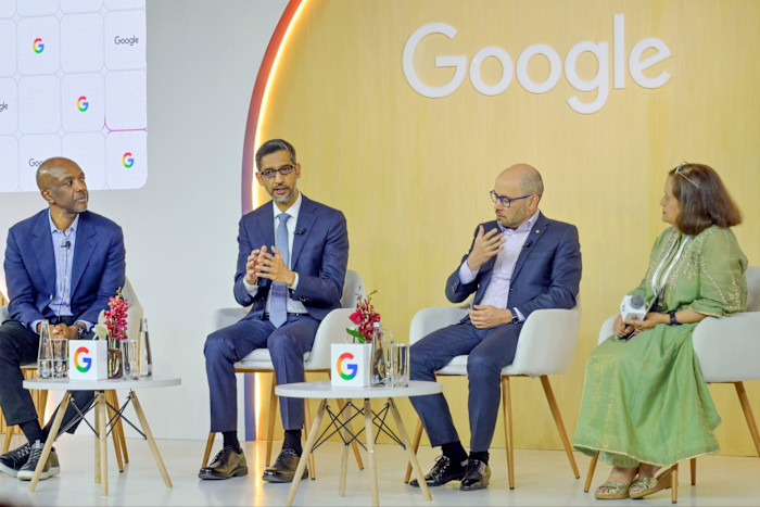 James Manyika, Sundar Pichai, Demis Hassabis and Debjani Ghosh seated on stage in conversation at a Google-branded event.