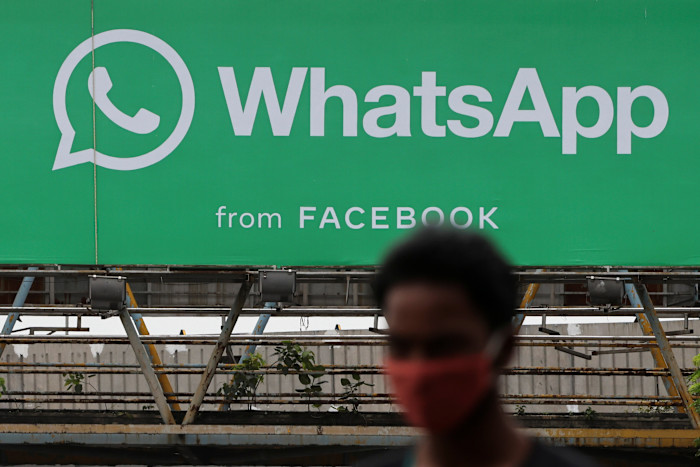 A man walks past a hoarding of the WhatsApp application installed at a skywalk in Mumbai, India, 