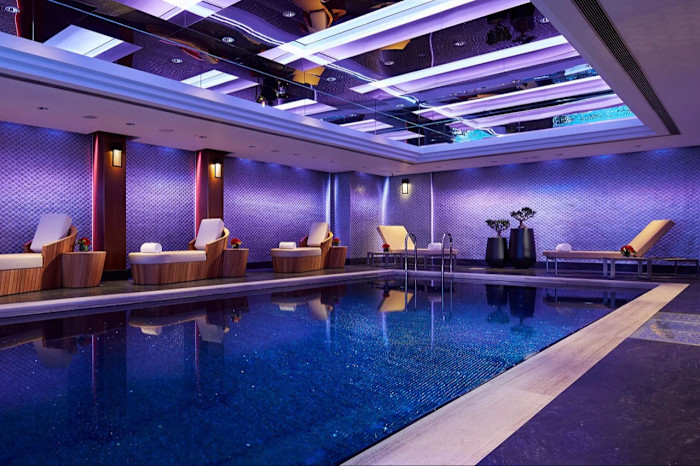 Detail of the hotel’s purple-lit indoor pool, with loungers around its edge