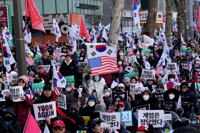 A large crowd of Yoon Suk Yeol supporters hold South Korean and US flags and signs, including “YOON AGAIN,” outside Seoul Central District Court.