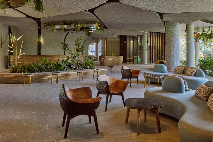 A hotel lobby featuring organic-shaped furniture, greenery, wooden accents, and natural textures throughout the space.