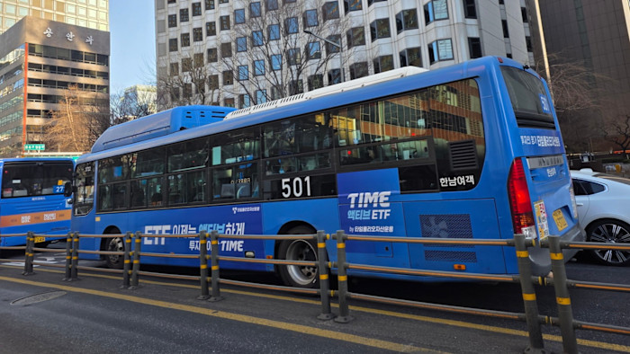 A blue Seoul city bus with an advertisement for TIME active ETF on its side, parked on a city street.