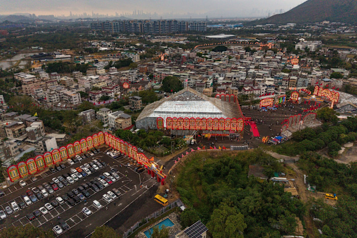 Aerial view of the world’s largest bamboo theatre in Kam Tin, with elaborate red and yellow decorations and a large parking lot.