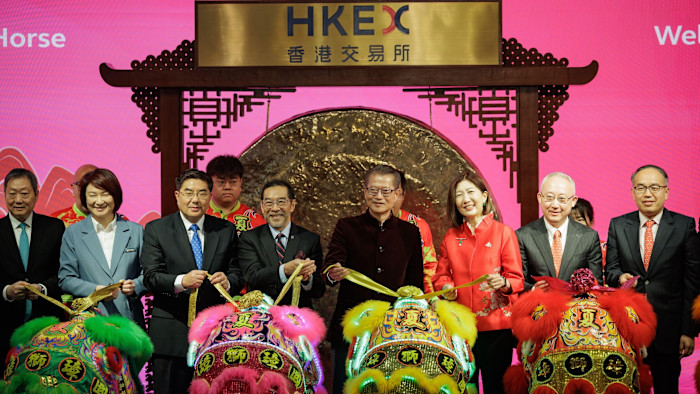 Carlson Tong, Paul Chan, and Bonnie Chan pose with others holding ribbons attached to colorful lion dance costumes at a ceremony for the first trading day of the Year of the Horse at HKEX.