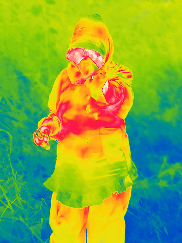 The outline of a person bathed in swirls of bright red, oranges and green against a blue and green background. The image was created by using thermal imaging to evoke the invisible presence of radiation
