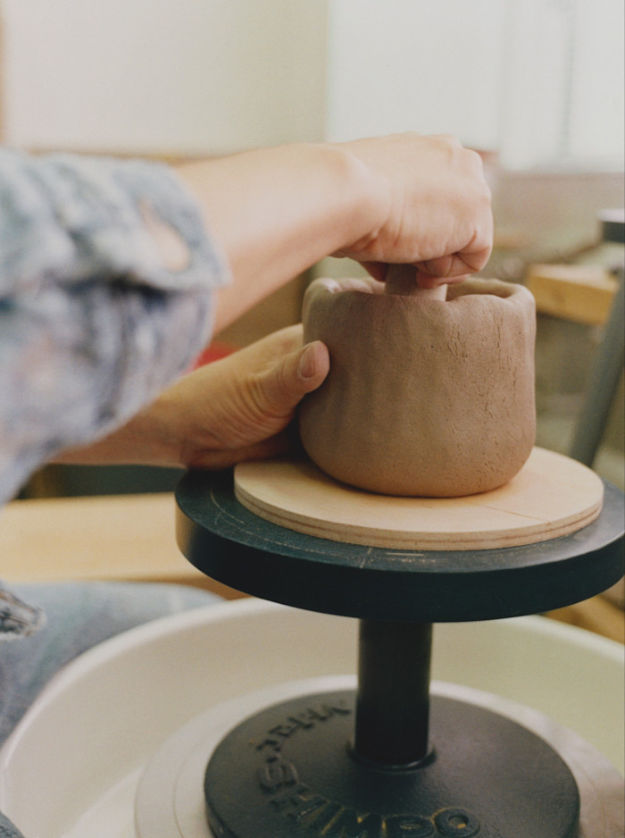 Shaping a pot on the wheel in his ceramics studio