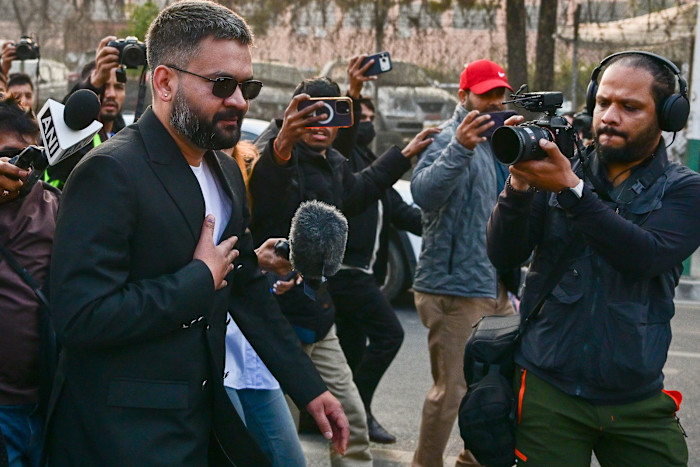 Balendra Shah, wearing sunglasses and a black jacket, is surrounded by media and photographers after casting his vote.