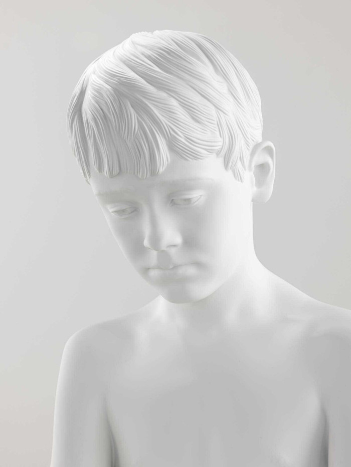 Close up of a white sculpture of a boy. 