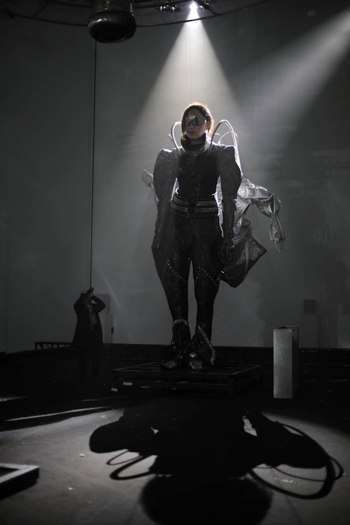A large-scale installation by Tim Yip titled "Lili" features a futuristic, armored humanoid figure standing under a spotlight, casting a dramatic shadow.