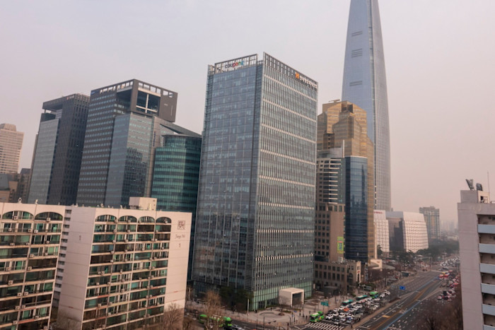 Coupang headquarters building in Seoul among other high-rise offices, with a busy street and residential building in front.