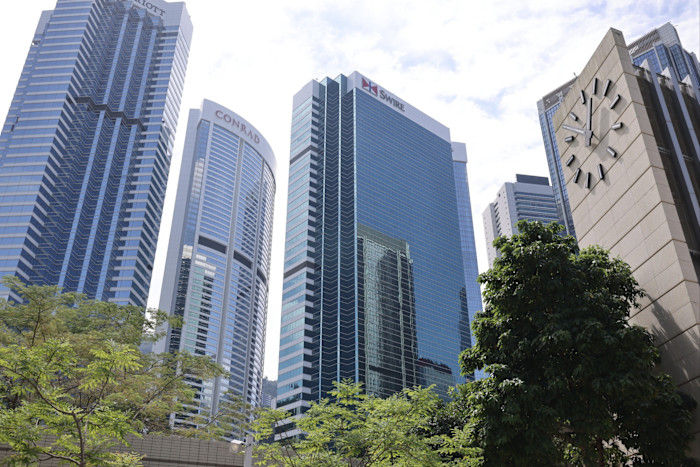 High-rise office towers at One Pacific Place, Admiralty, with a large outdoor clock and trees in the foreground.