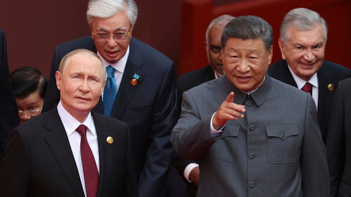 Vladimir Putin, Kassym-Jomart Tokayev, Xi Jinping, and Shavkat Mirziyoyev walk together, with Xi Jinping pointing ahead.